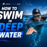 Man swimming in deep water wearing swim cap and goggles.